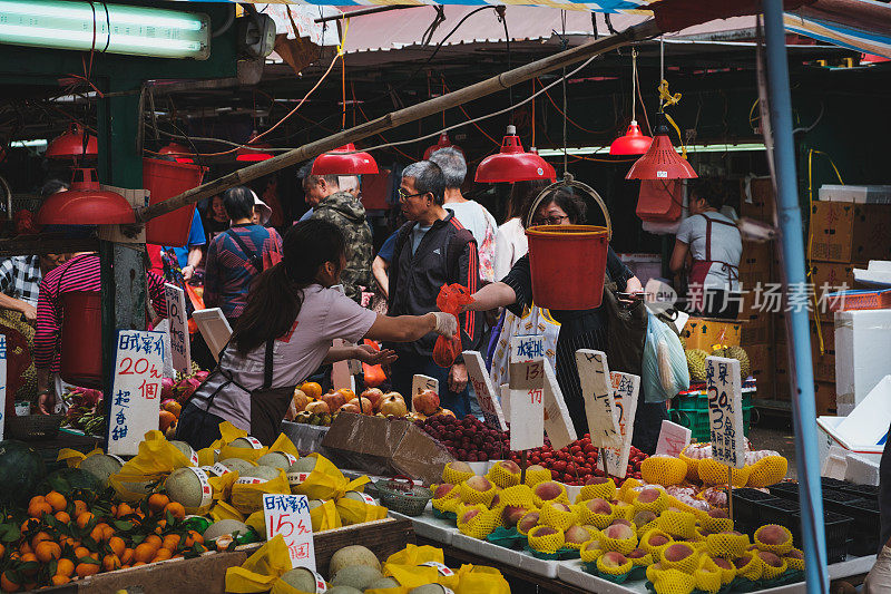 人们在香港的街头食品市场上购买蔬菜和水果