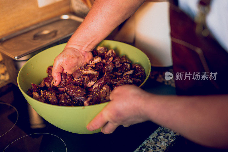 这是一名男子用手将生肉和所有香料混合在碗里的细节照片