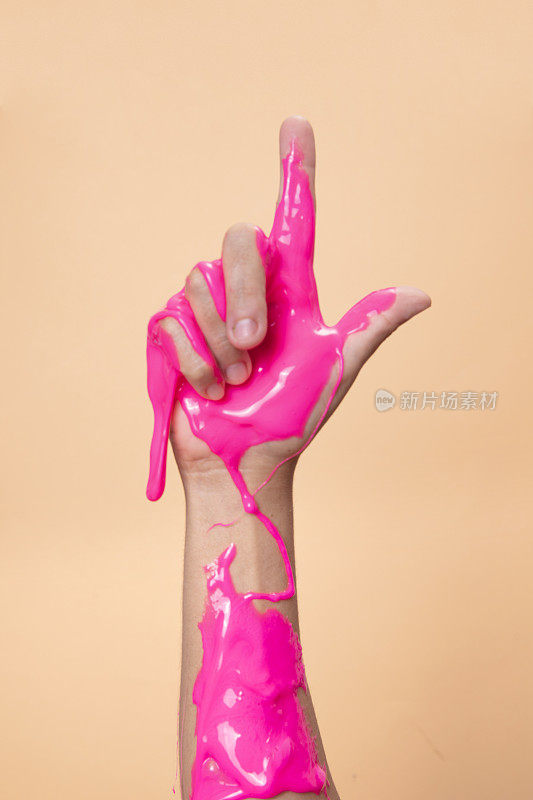 手显示2与霓虹粉色黏液玩具在橙色波普艺术背景。