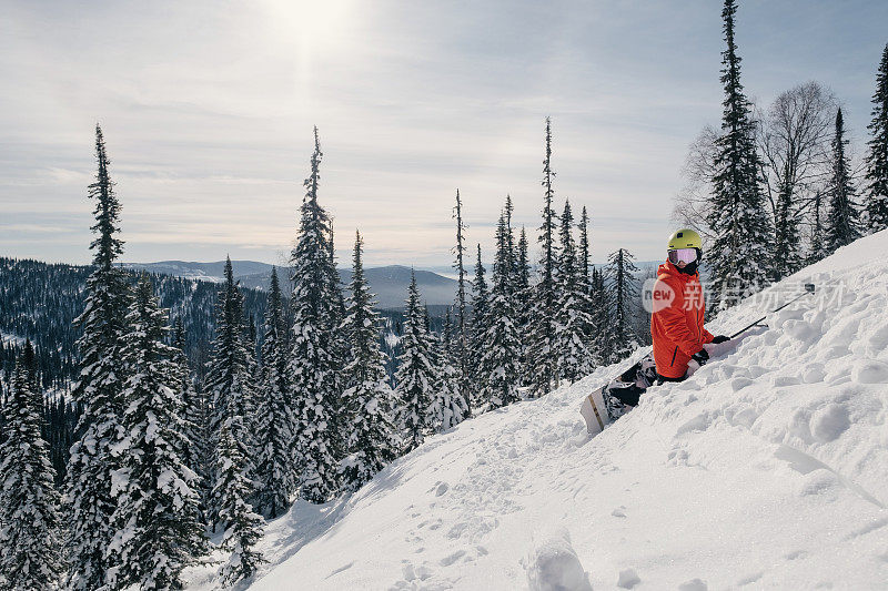 冬季阳光明媚的日子里，滑雪板自由骑手爬山