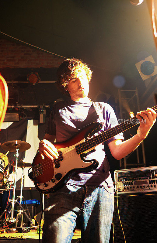 一个年轻人在一场摇滚表演的舞台上热情地弹着贝斯吉他