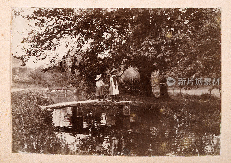 19世纪90年代，女孩们在小溪上走过脚桥的原始古董照片