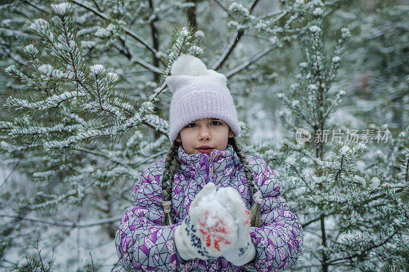 冻僵的女孩穿着暖和的衣服，带着期待已久的第一场雪，在森林里漫步，冬天的仙境