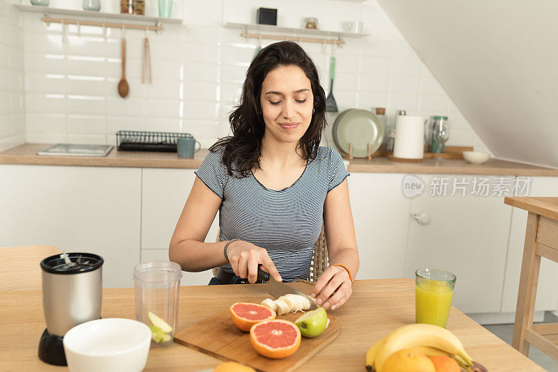 快乐的年轻女人在做奶昔当早餐