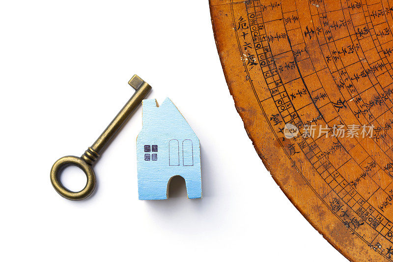 蓝色木制微型房子和古董钥匙与古老的中国风水罗盘板在白色背景上