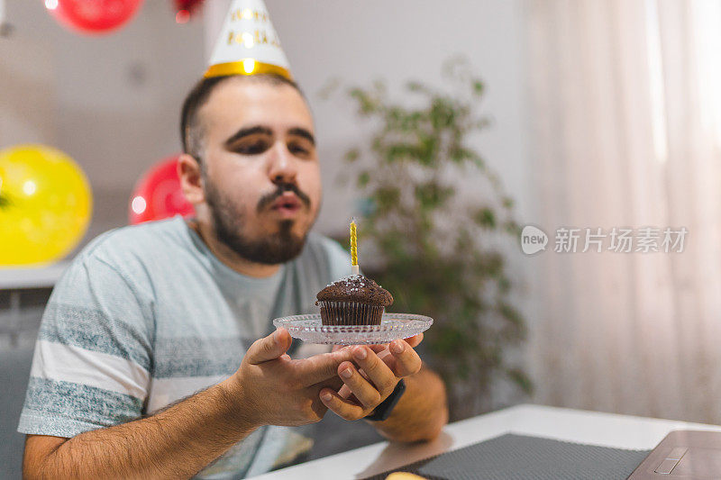 一名年轻人在家中庆祝生日时吹灭了自制生日蛋糕上的蜡烛