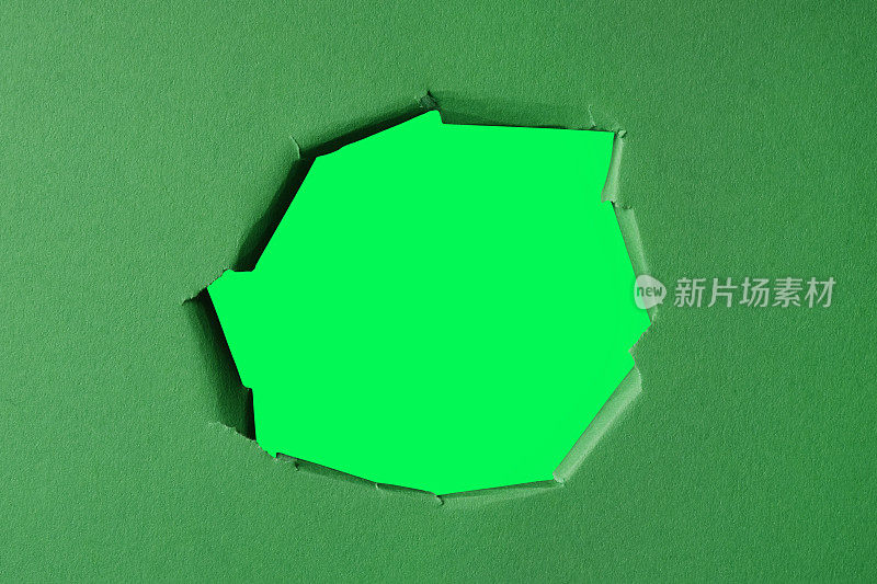 在绿色的硬纸板上撕开一个洞。绿色撕裂纸洞黄色背景。(带剪切路径的孔洞)