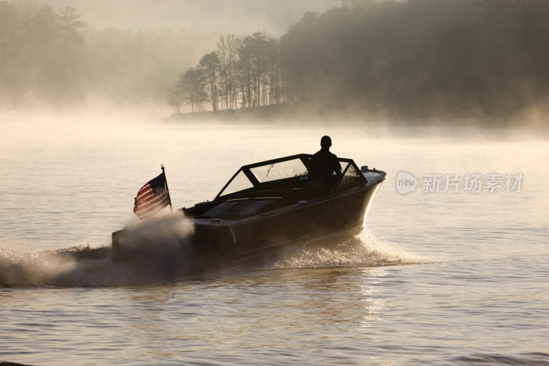 黎明时分，一名男子独自驾驶快艇在雾蒙蒙的湖面上行驶