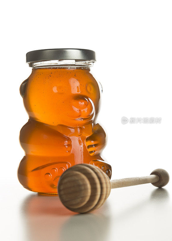 蜂蜜熊(罐子)，蜂蜜勺放在一边，白色上孤立。