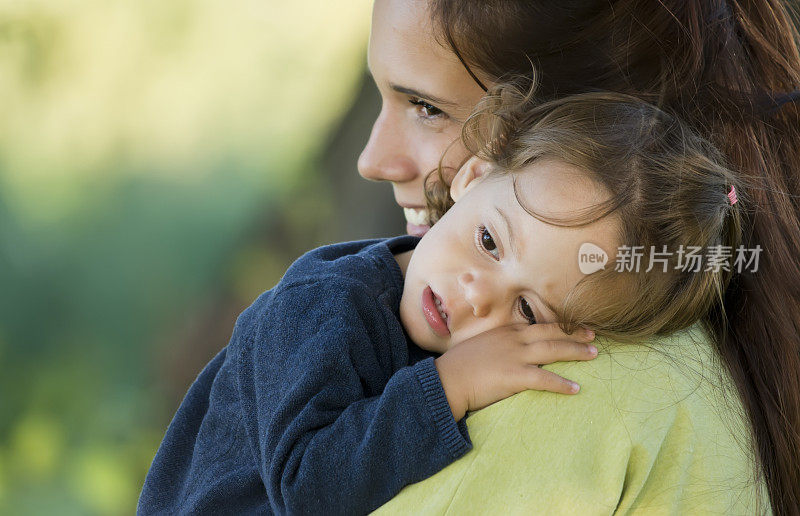 可爱的小女孩靠在妈妈的肩膀上