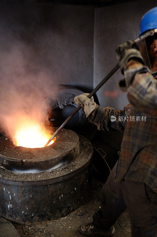 铸造工人搅拌熔化的金属