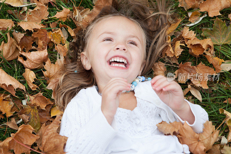 小女孩在秋叶中欢笑