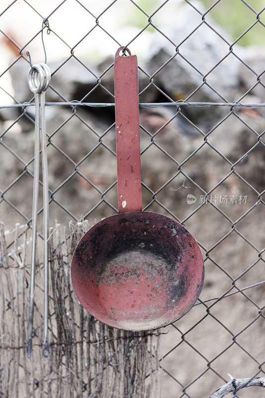 一个生锈的旧煎锅挂在篱笆上