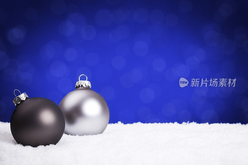 银色和黑色的圣诞装饰物上的雪，蓝色的背景