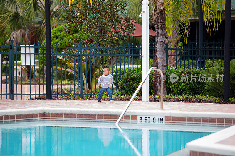 蹒跚学步的小男孩进入上锁的大门，绕着游泳池走