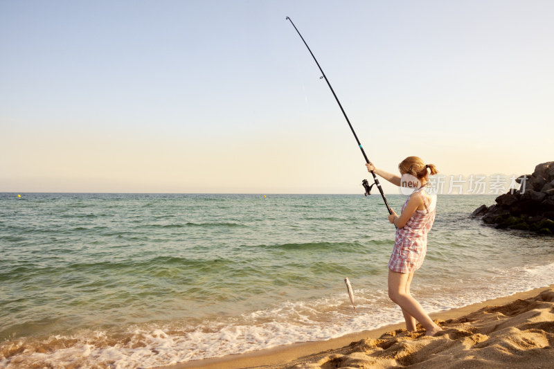 年轻女孩在海滩钓鱼