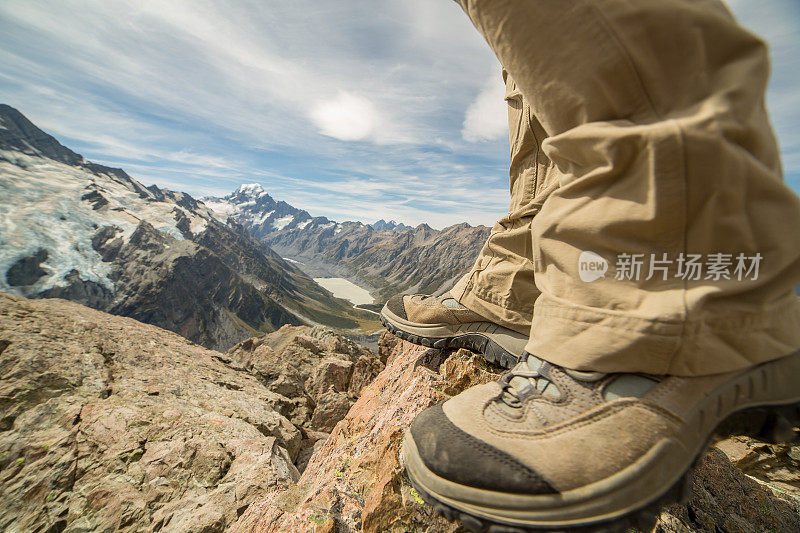 徒步旅行者的腿和靴子站在山顶上