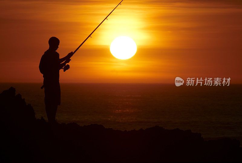 男孩在夕阳下出海捕鱼