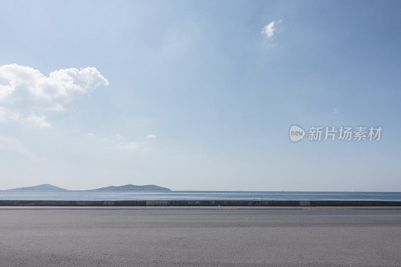 一个阳光明媚的日子，空旷的沥青停车场与海边背景