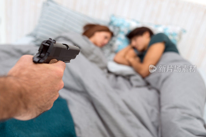 强盗用枪指着床上的一对夫妇