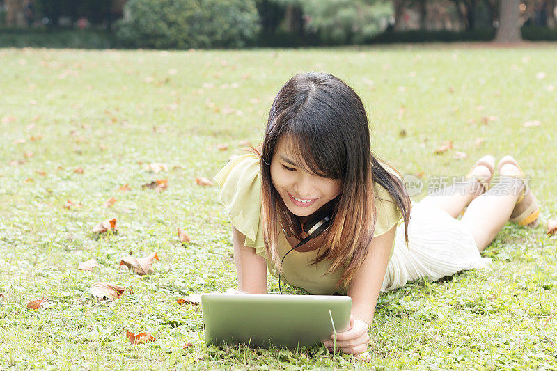 亚洲年轻女学生用平板电脑享受音乐。