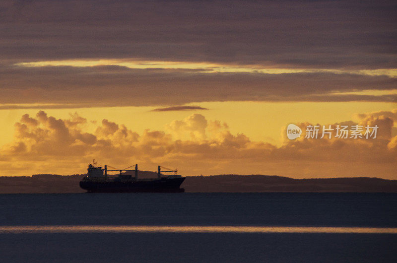 海面上的日出和地平线上的油轮