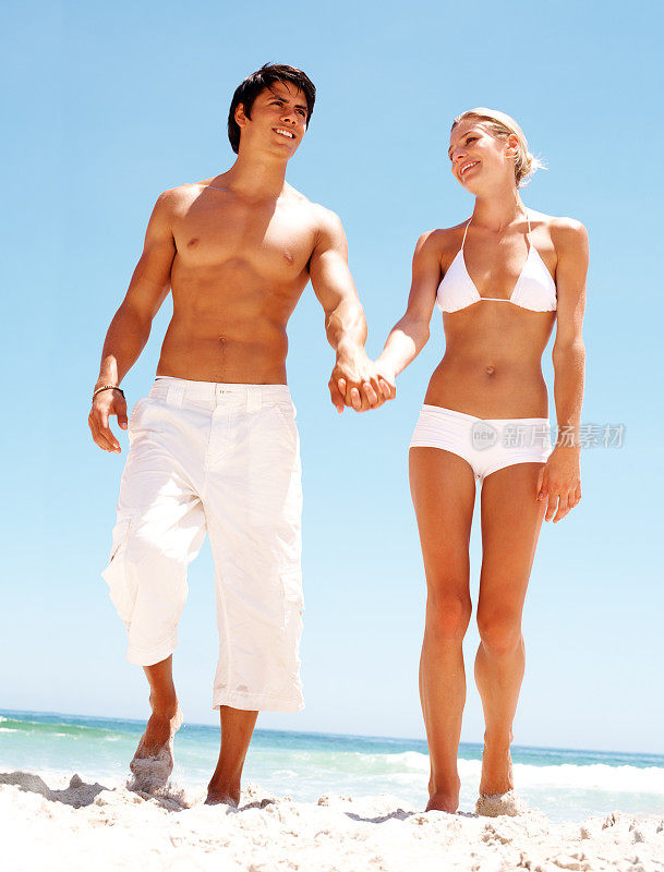 一对幸福的夫妇手牵着手在岸边散步