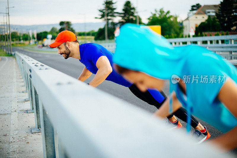 一对夫妇在高速公路的围栏上做俯卧撑