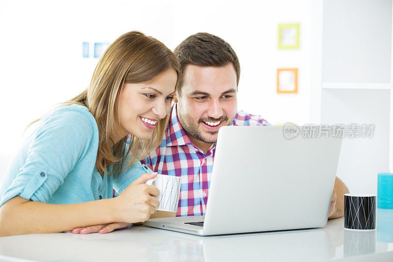 欢快的年轻夫妇使用笔记本电脑。