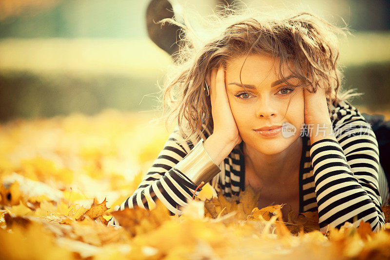 美丽的女人带着秋叶微笑着