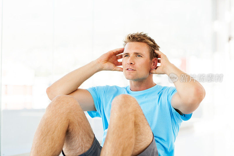 男人在健身房做仰卧起坐时看向别处