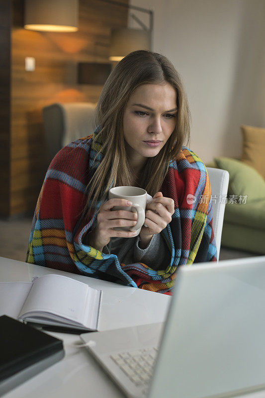 患流感的妇女端着热茶在家用笔记本电脑工作
