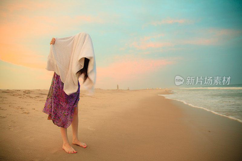 年轻女孩在海滩上用毛巾擦干头发