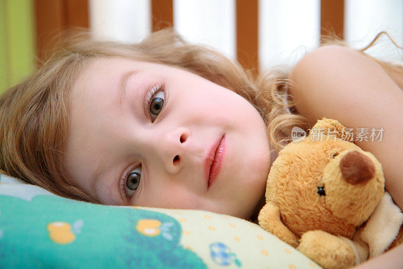 3-6岁的女孩和泰迪熊躺在床上