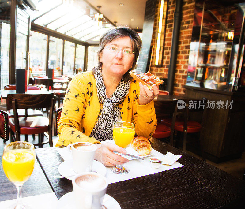 年长妇女享受欧式早餐在咖啡馆，巴黎