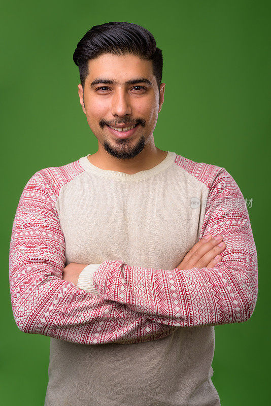 年轻的留胡子的伊朗男子穿着休闲衣服，背景是绿色