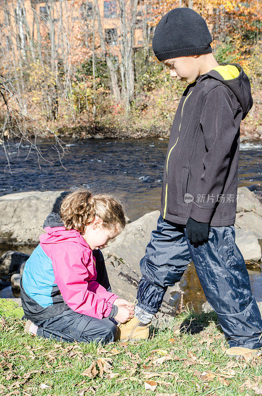 秋天的一天，魁北克市圣查尔斯河边，女孩在为她哥哥的表演镶边