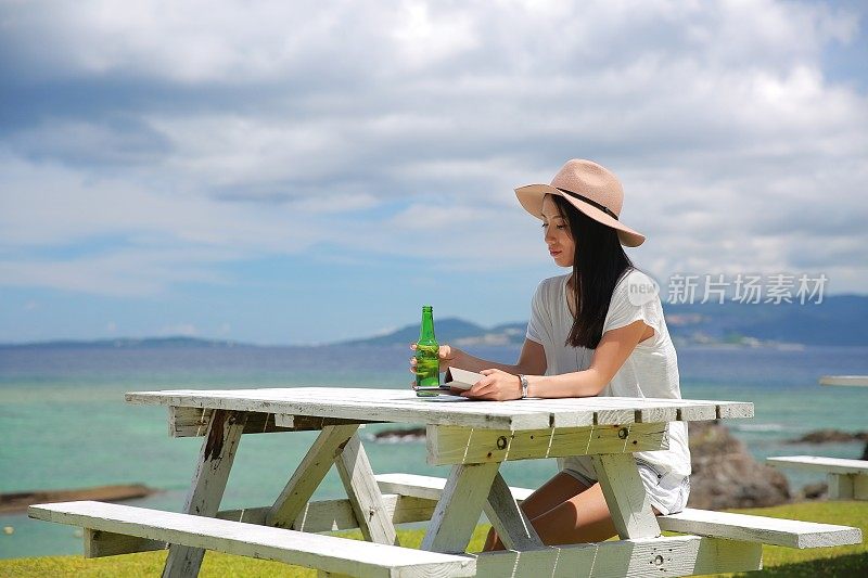 一位年轻的日本妇女在一张白色的长凳上等候。