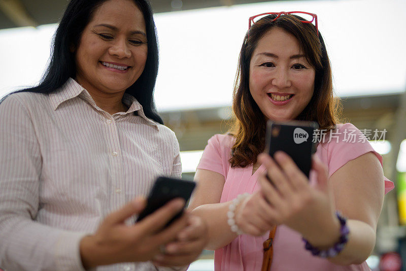 两个成熟的亚洲女性朋友在泰国曼谷防弹少年团轻轨站的肖像