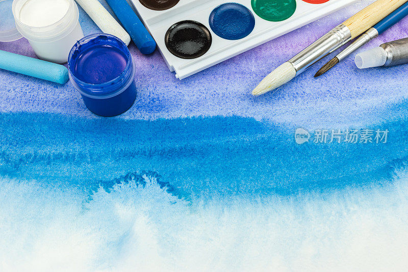 水彩画调色板与画笔在蓝色水彩手绘背景