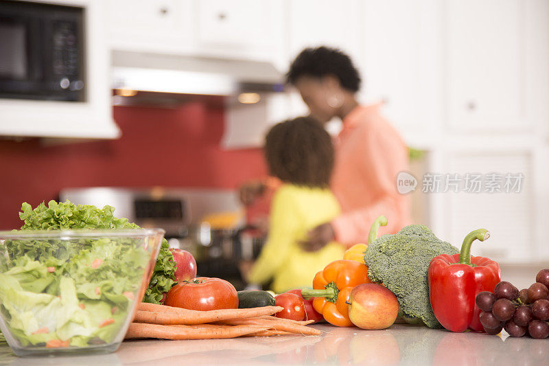 祖母或母亲和女儿一起在家里厨房做饭。