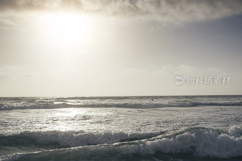菲斯特拉海滩，纽基，康沃尔近日落，遥远的冲浪者在海上。