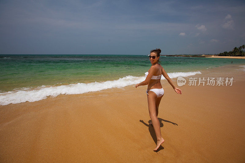 一个穿着白色比基尼的女人正在海边玩