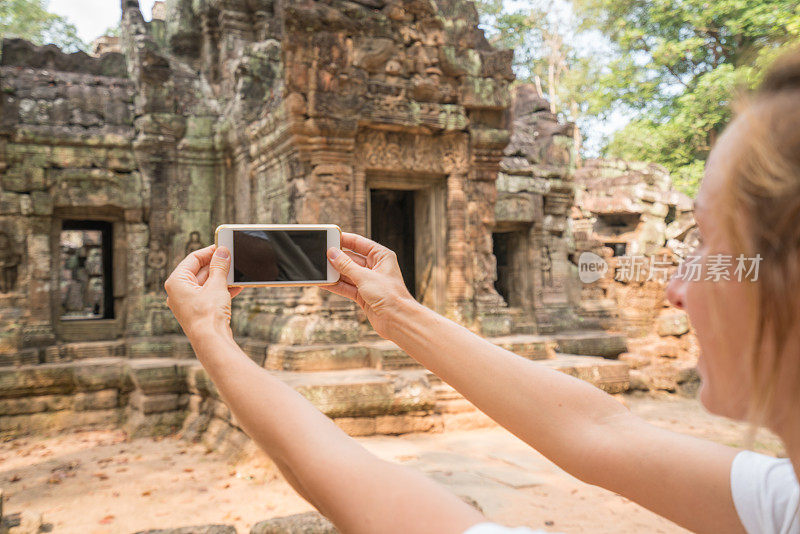 一名年轻女子在柬埔寨吴哥窟的寺庙观光中用智能手机拍照