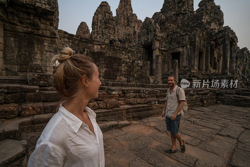 一对在亚洲旅游的游客，在夕阳下凝视美丽的古庙和古老的废墟;人发现探索理念