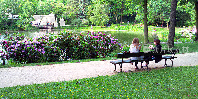 两个女人坐在公园的长椅上。