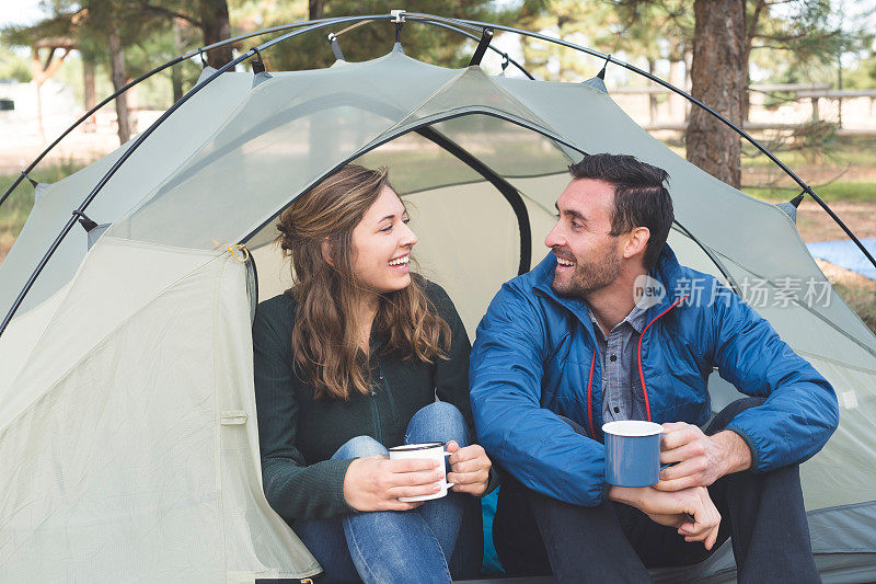 这对千禧一代夫妇在露营旅行中坐在帐篷里喝咖啡
