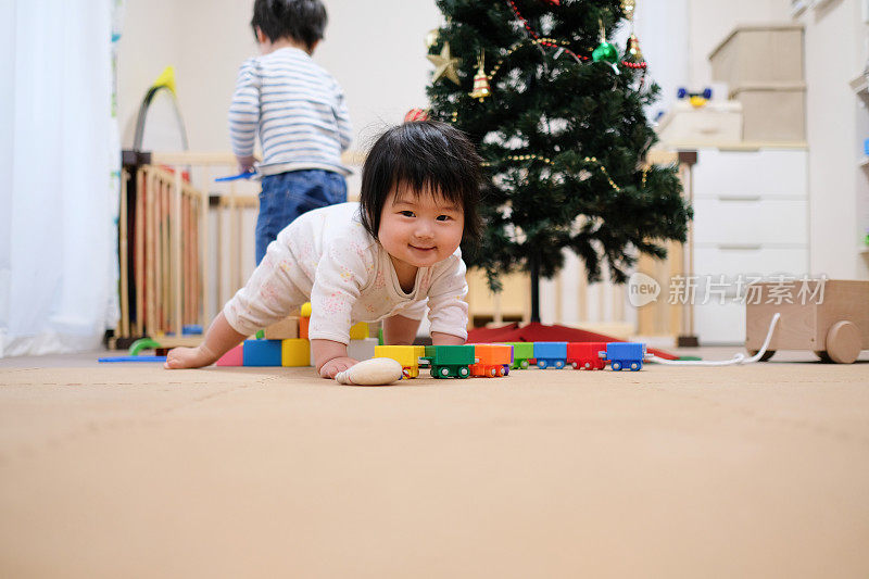 圣诞节时婴儿和蹒跚学步的孩子在客厅玩玩具