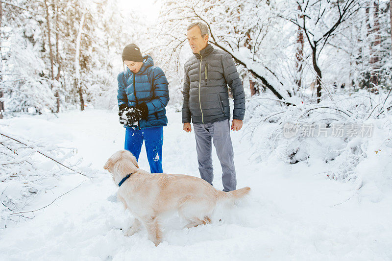 一家人和他们的狗在公园玩雪球