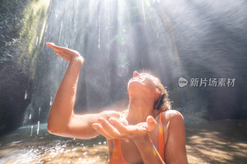 热带雨林里的年轻女子仰望着美丽的阳光用手触摸着雨滴。人们旅游是享受自然和生活的理念